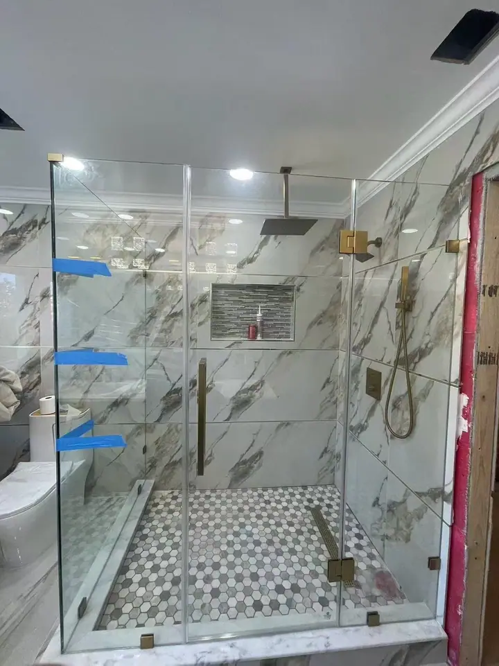 Corner enclosure with brushed gold hardware installed by Merlord