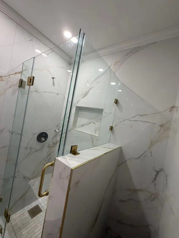 Half wall with brushed gold hinged door installed by Merlord